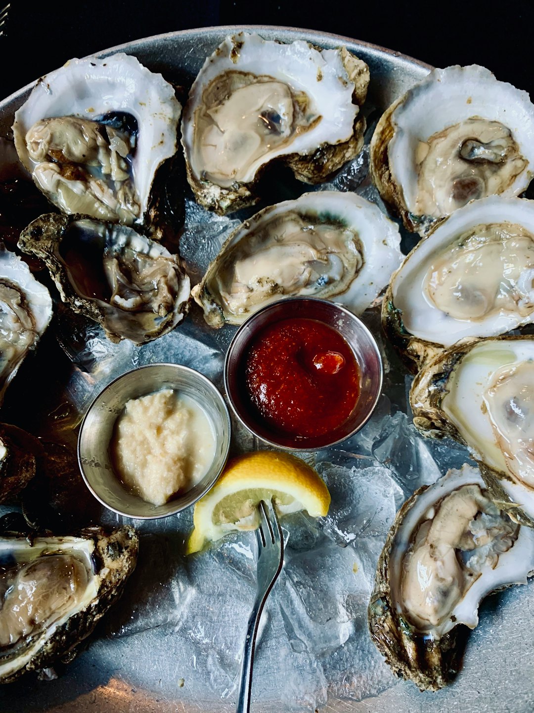 Freshly shucked oysters served on ice with sauces and lemon.