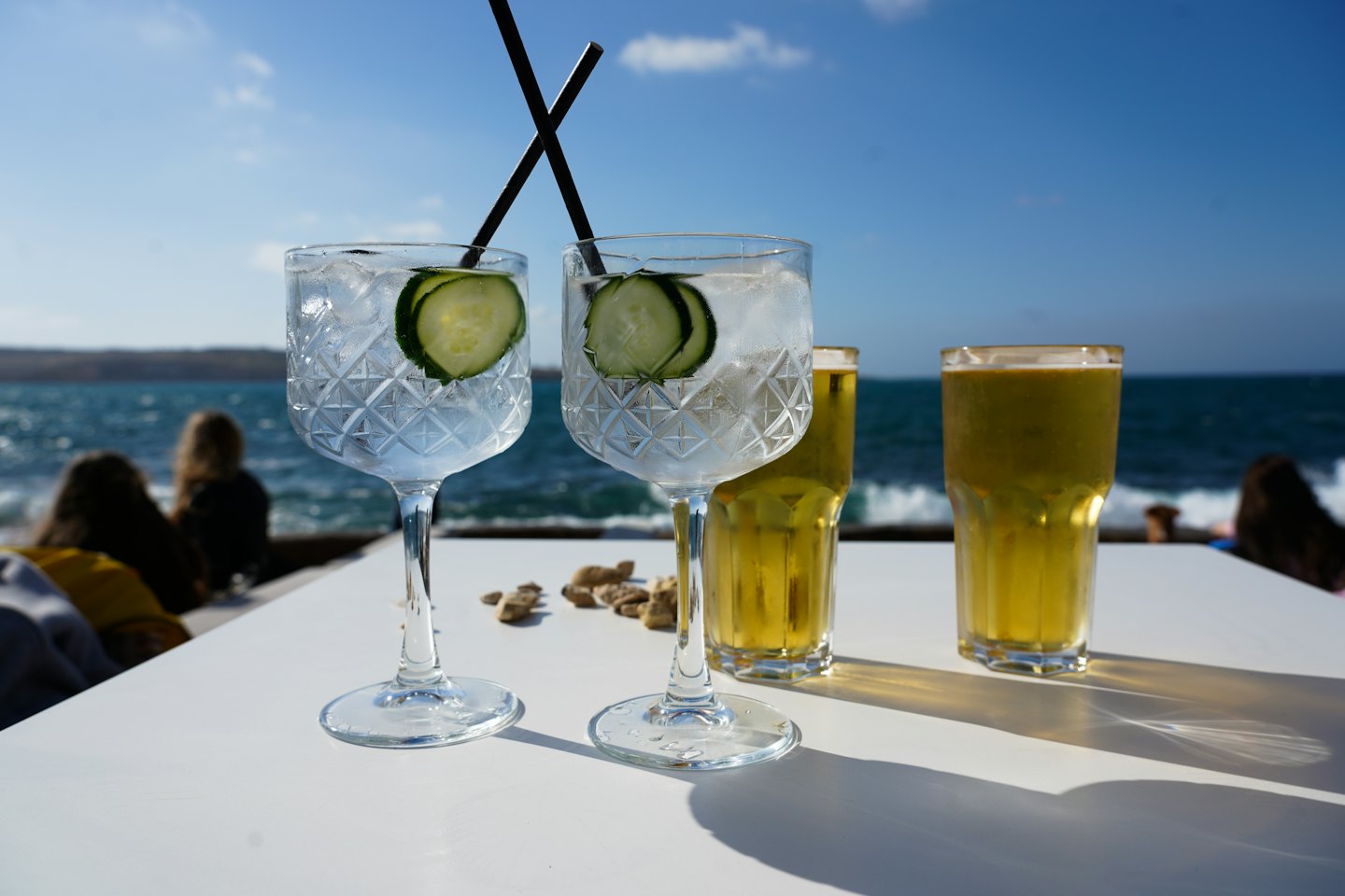 Gin and tonic glasses and beer pints on a table.