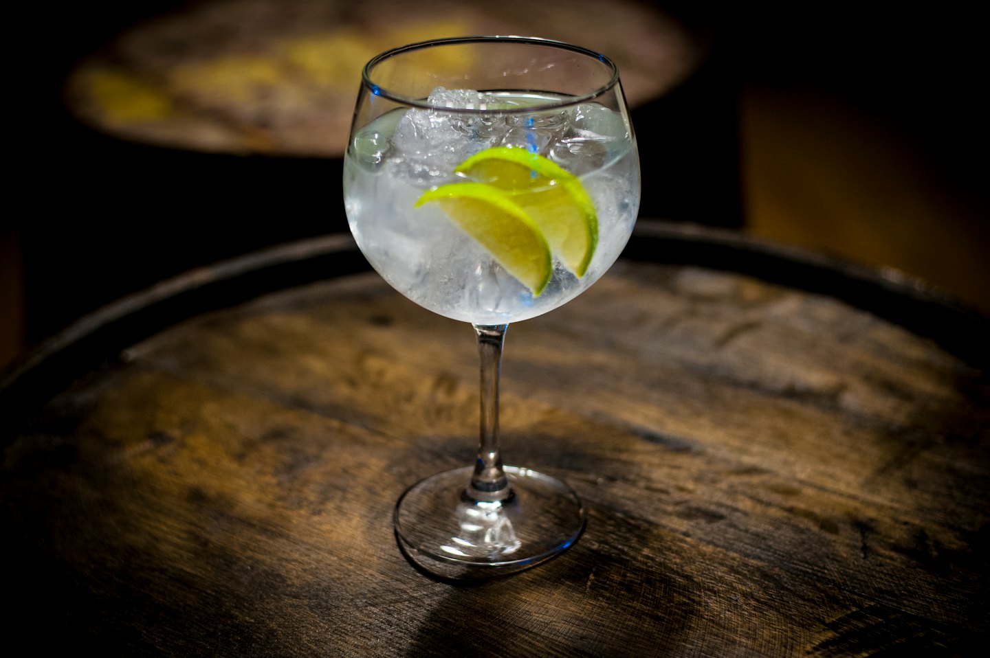 Gin and tonic cocktail with lime on a wooden barrel.