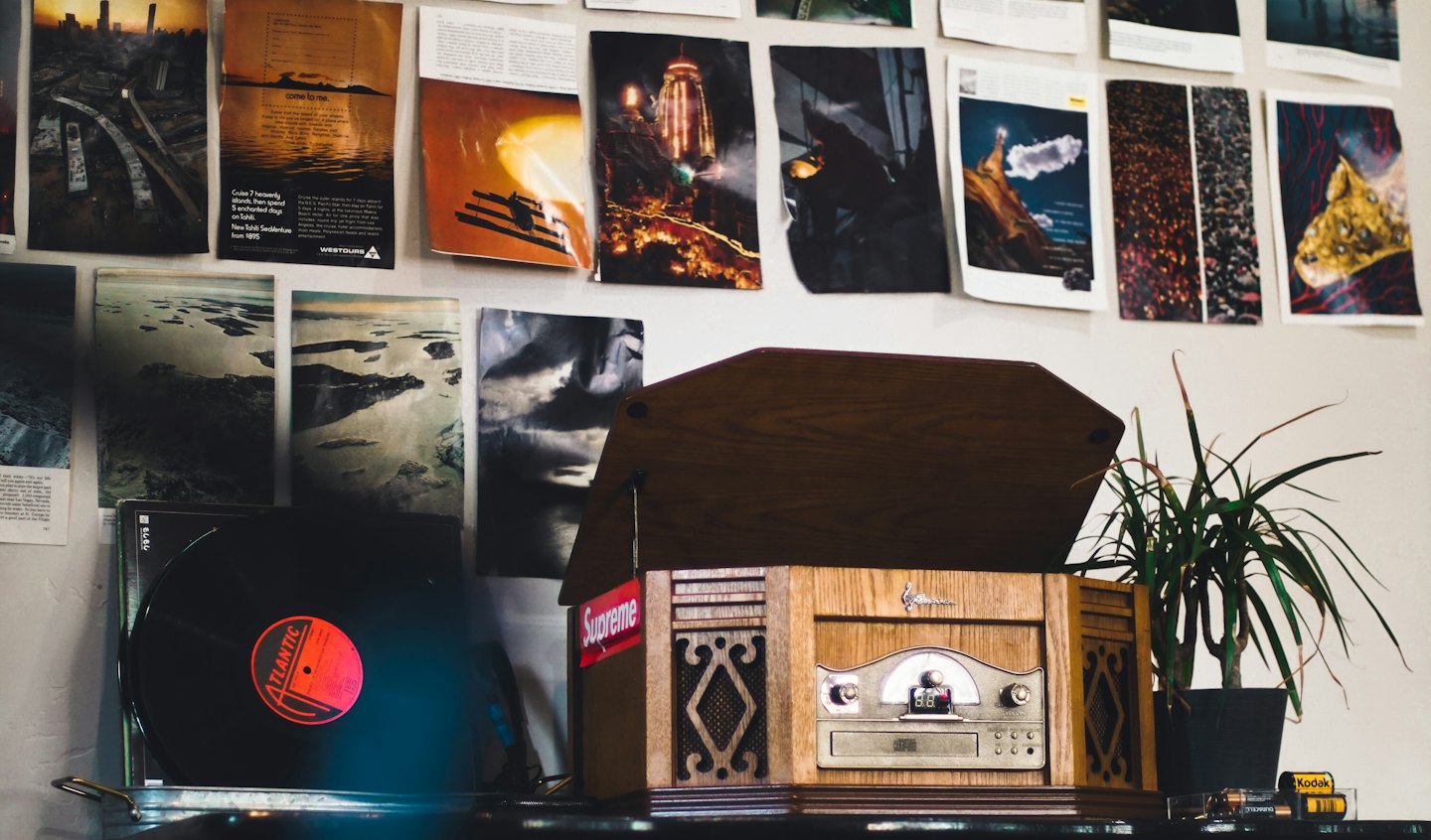 Vintage record player with vinyl and a plant on a desk.